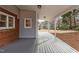 Covered back porch featuring a gray wood floor, brick exterior, and white support columns at 100 Royall Rd, Oxford, NC 27565