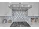 Close-up of a modern kitchen with stainless steel appliances, mosaic backsplash, and quartz countertops at 10210 Sablewood Drive # 112, Raleigh, NC 27617