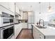 Modern white kitchen with stainless steel appliances, hardwood floors, and sleek countertops with pendant lights at 10210 Sablewood Drive # 112, Raleigh, NC 27617