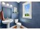 Stylish half bathroom features blue patterned wallpaper, a pedestal sink, and a bright window at 1028 Zelkova Ln, Chapel Hill, NC 27517