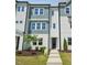 A modern, three-story townhome with a light blue and white facade, and a manicured lawn at 1028 Zelkova Ln, Chapel Hill, NC 27517