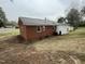 Brick ranch home featuring mature landscaping, windows, and an attached storage unit at 103 Beam Cir, Louisburg, NC 27549