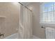 Tiled bathtub and shower combination with a decorative curtain and a window at 10540 Byrum Woods Dr, Raleigh, NC 27613