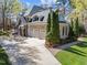 Large driveway leading to a three-car garage with well-maintained lawn and mature trees at 10540 Byrum Woods Dr, Raleigh, NC 27613
