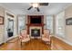 Cozy living room showcasing a fireplace, chairs, and hardwood flooring and natural light at 10540 Byrum Woods Dr, Raleigh, NC 27613