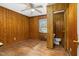Wood-paneled bedroom featuring a ceiling fan and adjacent half bathroom at 1101 Nashville Rd, Rocky Mount, NC 27803