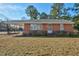 Charming brick home with mature landscaping featuring a covered parking area on a sunny day at 1101 Nashville Rd, Rocky Mount, NC 27803