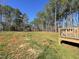 Expansive backyard with a mix of grass and bare earth, bordered by tall trees and a wooden deck at 112 Wichita Way, Louisburg, NC 27549