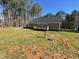 View of backyard featuring a gray house with a deck and a spacious lawn bordered by tall trees at 112 Wichita Way, Louisburg, NC 27549