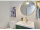 Charming bathroom with green vanity, round mirror, and modern gold faucet at 1301 Flying Hawk Rd, Apex, NC 27523