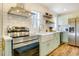 Well-lit kitchen with stainless steel appliances, farmhouse sink, and floating shelves at 1301 Flying Hawk Rd, Apex, NC 27523