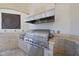 An outdoor kitchen features a stainless steel grill with a stone backsplash and decorative art piece at 1404 Barony Lake Way, Raleigh, NC 27614