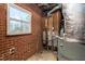 Unfinished basement featuring exposed brick, visible piping, and a window allowing natural light in at 1506 N Mebane St, Burlington, NC 27217