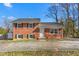 Traditional brick home with black shutters and mature trees under a bright blue sky at 1506 N Mebane St, Burlington, NC 27217