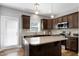 Modern kitchen boasts a central island, stainless appliances, and dark cabinetry, all illuminated by a bright window over the sink at 1613 Osprey Ridge Dr, Willow Springs, NC 27592
