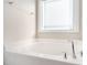 A pristine white bathtub with chrome fixtures sits beneath a frosted window at 19 Tobenton Ct, Clayton, NC 27520