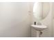 A clean half-bathroom with pedestal sink, modern fixtures, and a round mirror at 19 Tobenton Ct, Clayton, NC 27520