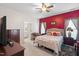 Main bedroom featuring a tray ceiling, red accent wall, ceiling fan, and en-suite bathroom at 1945 Red Quartz Dr, Raleigh, NC 27610
