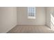 An empty bedroom featuring neutral carpet, light walls, and a window overlooking the yard at 195 Hawksmoore Ln, Lillington, NC 27546