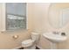 Bright powder room featuring pedestal sink, toilet, and natural light from the window at 2418 Pecan Ridge Way, Apex, NC 27502
