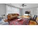 Cozy living room featuring a leather sofa, hardwood floors, ceiling fan, and a vibrant decorative rug at 256 Marilyn Cir, Cary, NC 27513