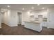 Open kitchen with granite island, white cabinets, and stainless sink with dark floors at 261 Canopy Dr, Graham, NC 27253