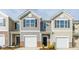 A lovely exterior shot of new townhomes featuring light colored siding, black shutters, and one car garages at 267 Canopy Dr, Graham, NC 27253
