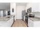 Efficient kitchen design with white cabinets, granite counters, stainless steel appliances, and luxury vinyl plank flooring at 31 Harrow Ter, Roxboro, NC 27574