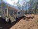 Back of home featuring a covered porch with wooden steps, overlooking a wooded lot at 3273 Argyll Dr, Sanford, NC 27332