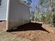 The side of a house showing brick foundation and a wooden basement door, surrounded by pine needle ground cover at 3273 Argyll Dr, Sanford, NC 27332