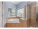 Bright bathroom featuring a soaking tub under a window and a glass-enclosed shower with tile surround at 4020 Abbey Park Way, Raleigh, NC 27612