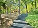 Backyard and steps leading to lake house, surrounded by lush greenery and mature trees at 48 Blue Heron Ln, Roxboro, NC 27574