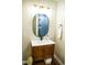 Bathroom vanity with a wood cabinet, white countertop, oval mirror, and decorative lighting at 48 Blue Heron Ln, Roxboro, NC 27574