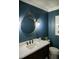 Chic powder room with a round mirror, stylish fixtures, and dark blue walls creating a sophisticated space at 48 Blue Heron Ln, Roxboro, NC 27574