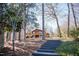 View of home with brick chimney surrounded by trees, showcasing elevated deck and long staircase entrance at 48 Blue Heron Ln, Roxboro, NC 27574