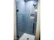 Modern shower with blue tile surround and built in shelf with toiletries at 48 Blue Heron Ln, Roxboro, NC 27574