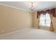 Light-filled bedroom with neutral carpet, large window, and decorative chandelier at 5036 Isabella Cannon Dr, Raleigh, NC 27612