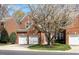 Classic two-story red brick home with a two-car garage surrounded by lush trees at 5036 Isabella Cannon Dr, Raleigh, NC 27612
