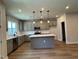 Modern kitchen boasts gray cabinetry, stainless steel appliances, a center island with white countertops, and stylish pendant lighting at 607 Callan View Ave, Wake Forest, NC 27587