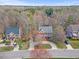 Aerial view showcasing a brick home with a circular driveway and mature trees in a residential neighborhood at 6116 Wilkinsburg Rd, Raleigh, NC 27612