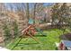 Spacious backyard with a playset, slide, swing, and a playhouse at 6116 Wilkinsburg Rd, Raleigh, NC 27612
