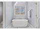 Relaxing bathroom with freestanding tub, window, and marble-patterned tiled flooring at 6116 Wilkinsburg Rd, Raleigh, NC 27612