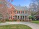Attractive brick home featuring mature landscaping, a circular driveway, and a welcoming front porch at 6116 Wilkinsburg Rd, Raleigh, NC 27612