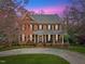 Stately two-story brick home with a welcoming front porch, black shutters, and manicured lawn at 6116 Wilkinsburg Rd, Raleigh, NC 27612