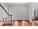 Bright foyer featuring hardwood floors, staircase with white railings, and transom windows at 6116 Wilkinsburg Rd, Raleigh, NC 27612