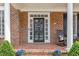 Close-up of a charming front porch with a decorative door, brickwork, and potted plants at 6116 Wilkinsburg Rd, Raleigh, NC 27612