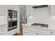 Bright kitchen with white cabinets, stainless steel appliances, a stovetop and hardwood floors at 6116 Wilkinsburg Rd, Raleigh, NC 27612