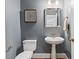 A powder room with pedestal sink, decorative mirror, and a toilet at 6116 Wilkinsburg Rd, Raleigh, NC 27612