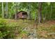 Secluded wood cabin with a porch and balcony surrounded by lush trees and nature at 6160 Virgilina Rd, Roxboro, NC 27574
