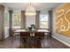 Elegant dining room with a modern chandelier, neutral decor, and views of the scenic outdoor landscape at 744 Ben Ledi Ct, Raleigh, NC 27603